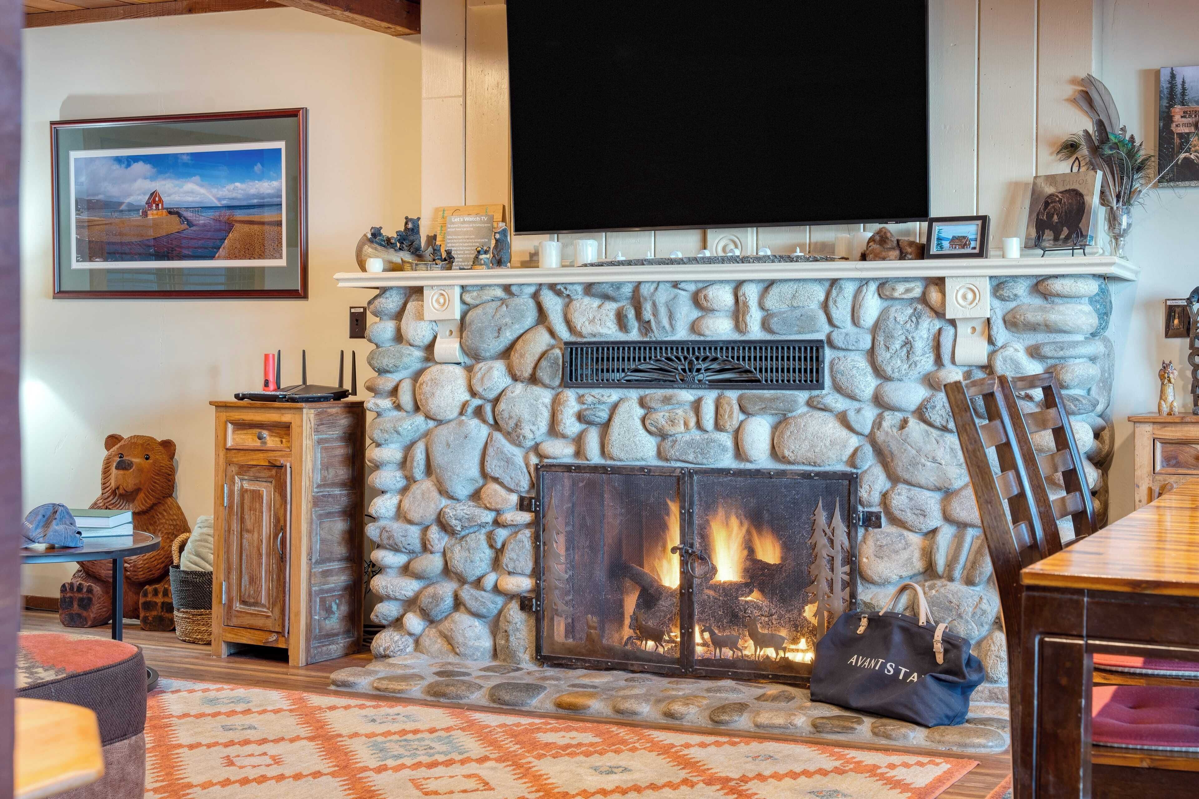 A stone fireplace with a TV above it, a large bear statue, and a rustic wooden cabinet.