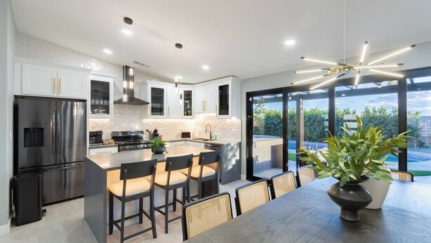 A modern kitchen with a central island, stainless steel appliances, and a view of a swimming pool. - Calypso by Avantstay Entertainers Paradise Pool, Hot Tub, Putting Green (Indio)