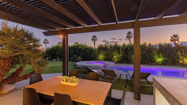An outdoor patio with a pool, seating, and a view of the surrounding landscape. - Calypso by Avantstay Entertainers Paradise Pool, Hot Tub, Putting Green (Indio)