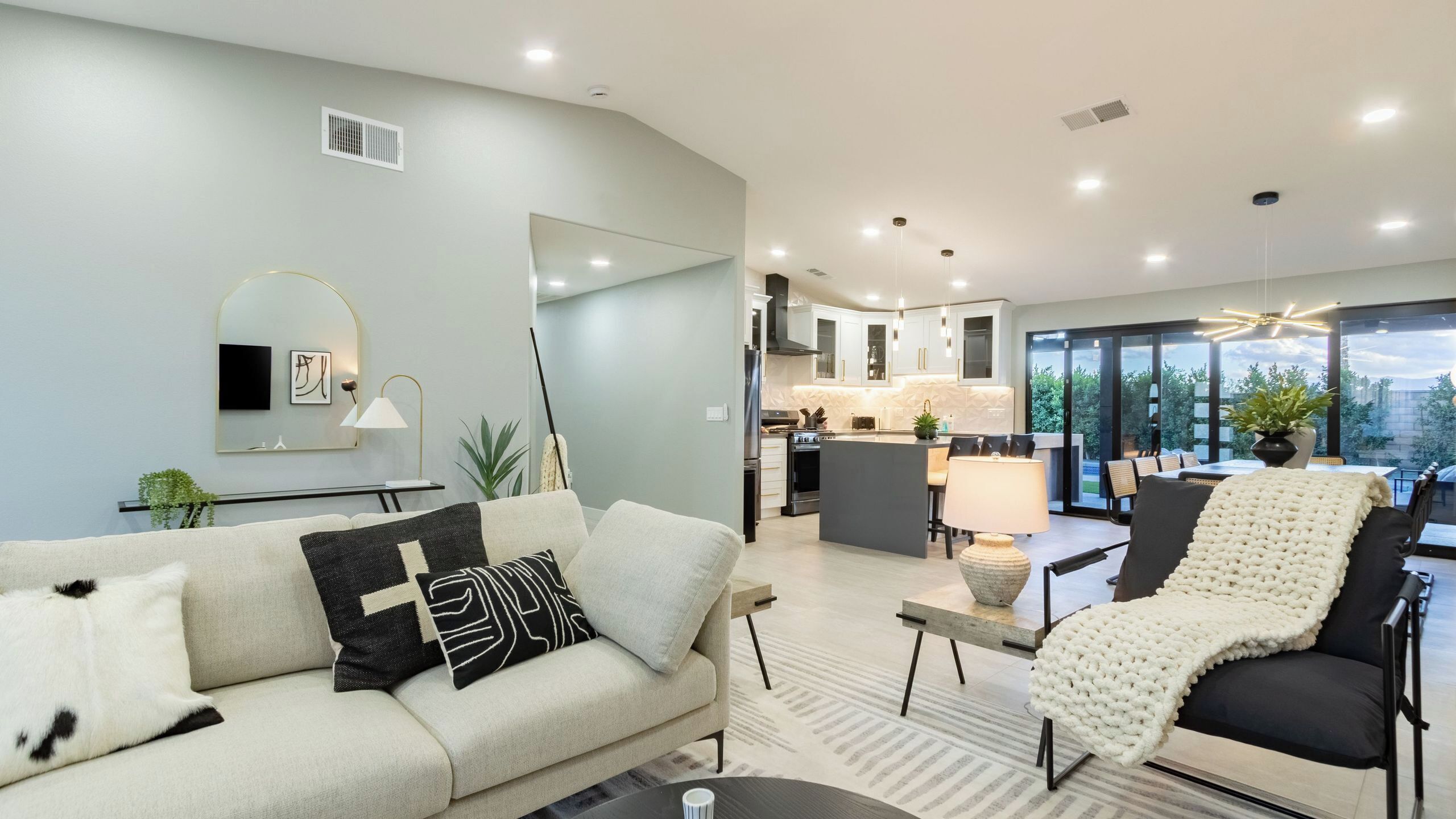 A modern living room with a sofa, a dining area, and a kitchen.