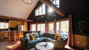 Une cuisine moderne avec des meubles en bois, un coin repas et un grand canapé d’angle.