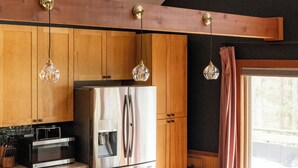 Une cuisine dotée de meubles en bois, d’appareils électroménagers en acier inoxydable, d’un îlot en marbre et de tabourets de bar en osier.