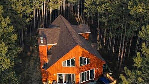 Une cabane en bois à deux étages, dotée d’une terrasse et entourée d’arbres.