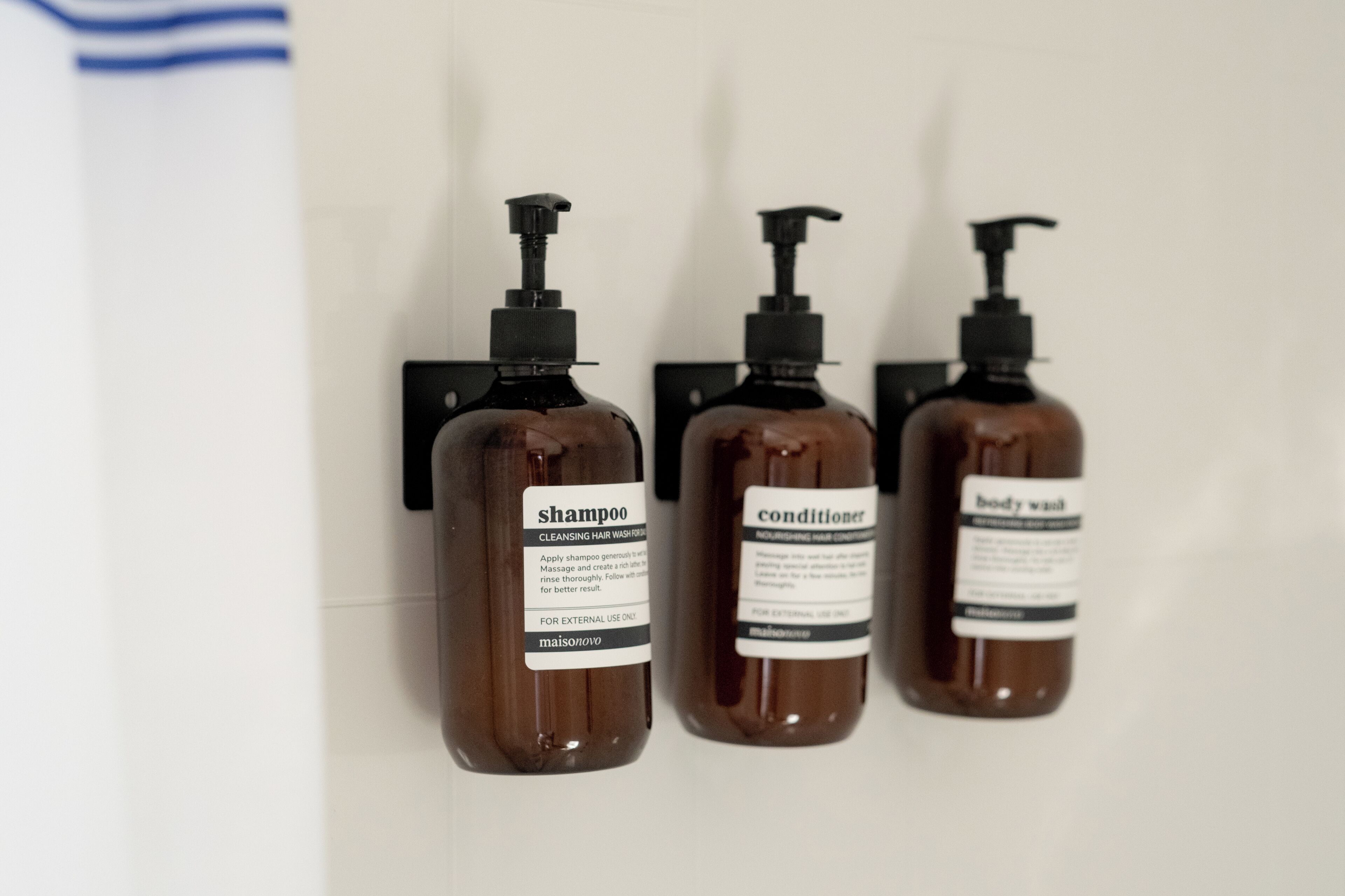 Three bottles of toiletries mounted on a wall.