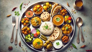 Variedad de platos de la India dispuestos en una bandeja metálica, incluyendo arroz, curries y panes planos, con cubiertos y salsas.