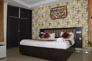 A bedroom with a large bed, a wardrobe, and a wall with a geometric pattern. - HOTEL GLOBAL STAY Near Delhi Airport (New Delhi)