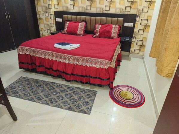 A bedroom with a large bed, a nightstand, a wall-mounted phone, and a patterned rug. - HOTEL GLOBAL STAY Near Delhi Airport (New Delhi)
