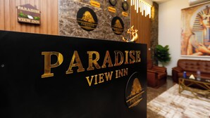 A reception desk with "PARADISE VIEW INN" signage, a stone wall with plaques, and a mural of an Egyptian figure. - Paradise Pyramids View INN  (Giza)