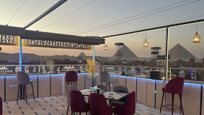A restaurant with a terrace overlooking a cityscape and a mountain. - Paradise Pyramids View INN  (Giza)
