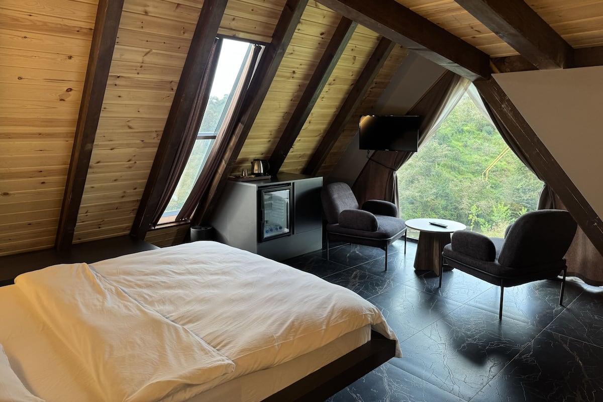 A bedroom with a bed, a TV, a chair, and a small table.