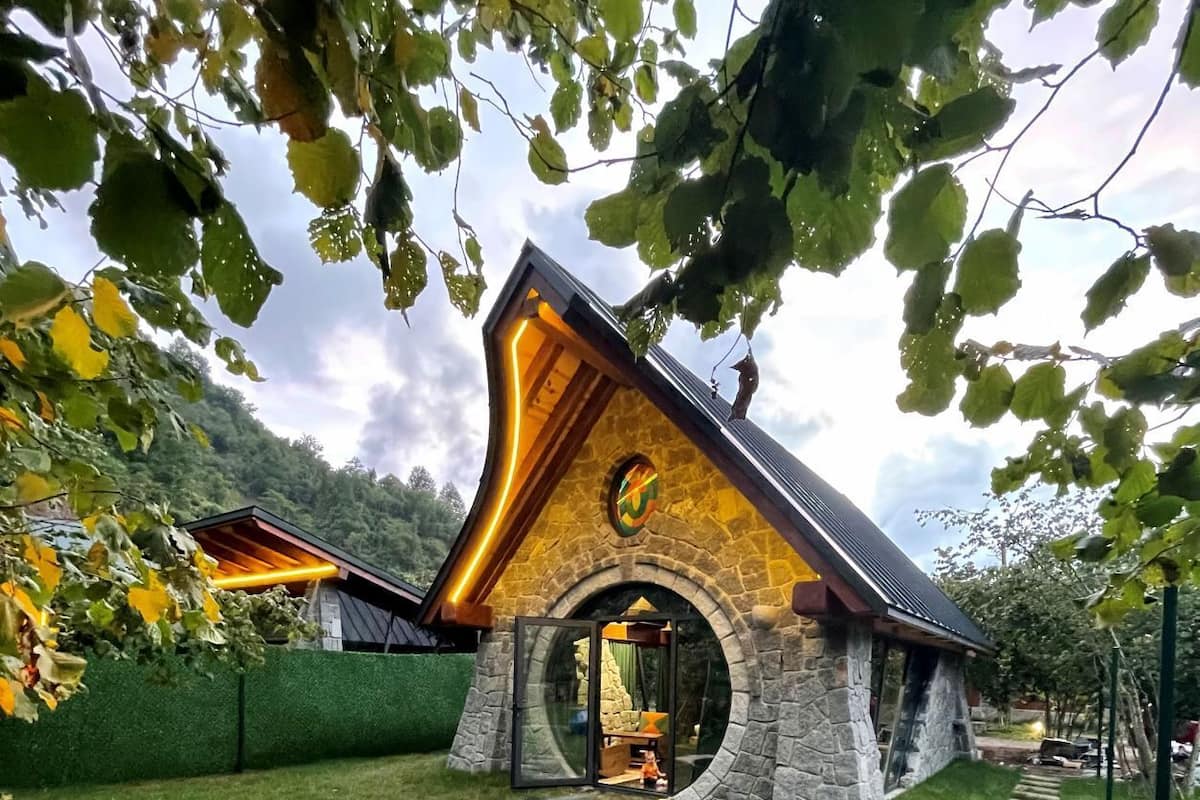 A stone building with a unique triangular roof and a circular window.