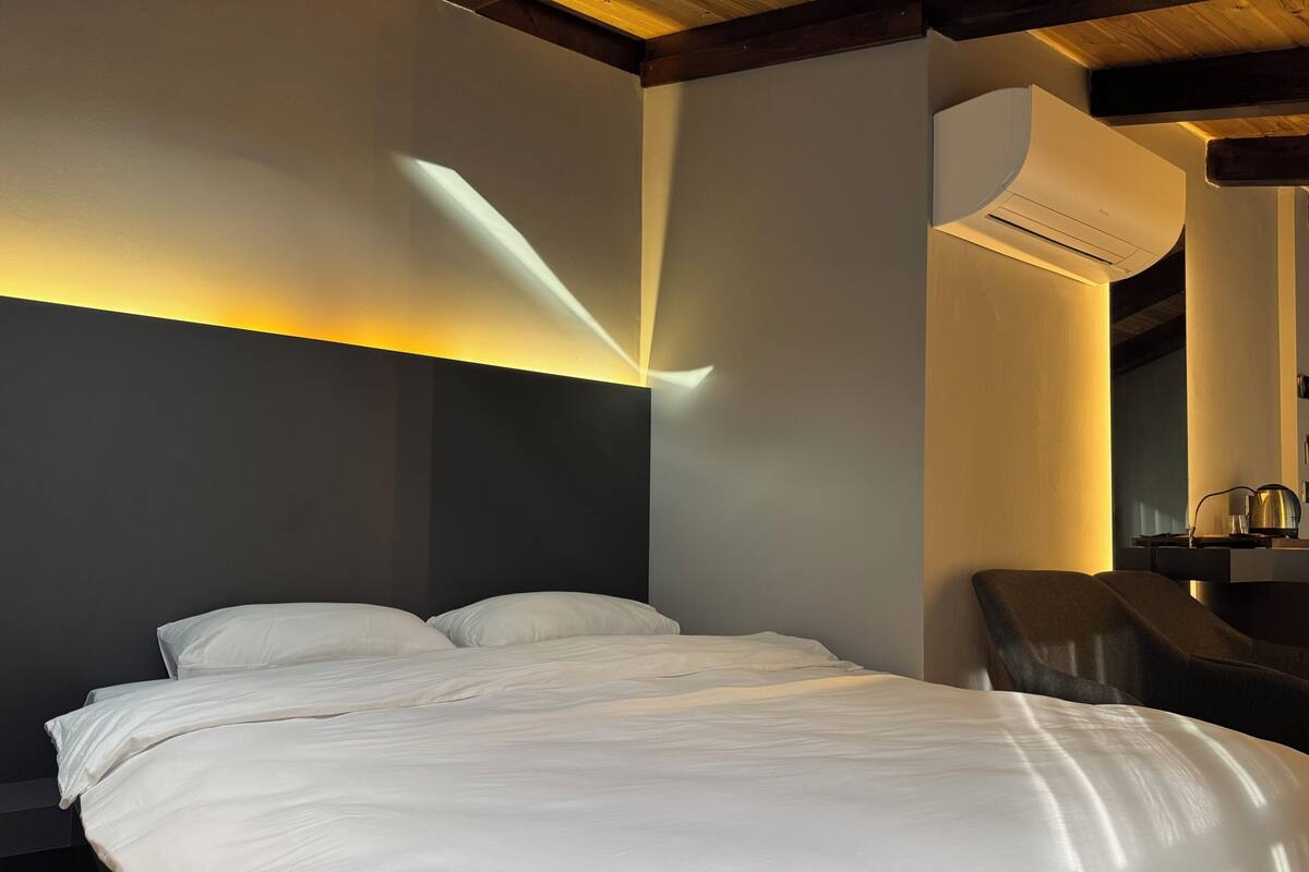 A modern hotel room with a large bed, a desk, and a chair.