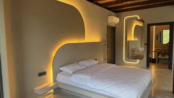 A modern bedroom with a minimalist design, featuring a large bed, built-in bedside tables, and a unique wall-mounted mirror.
