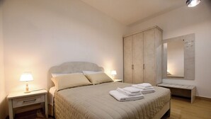 A bedroom with a bed, two bedside tables, a wardrobe, and a mirror. - GreSi's home - Holiday home, in the heart of medieval Tivoli (Tivoli)