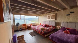 Ein Schlafzimmer mit Bett, Stuhl, Schreibtisch und Meerblick.