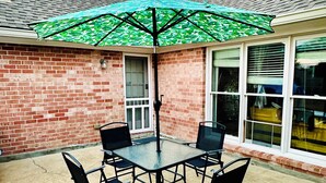A patio with a table and chairs, a green umbrella, and a brick wall. - Elegant Master Suite w/ Walk-in Closet & Private Entry in Prime Location MGM! (Montgomery)