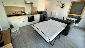 A modern, compact living space with a kitchenette, a bed, and a dining area.