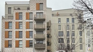 A multi-story residential building with balconies, a brick facade, and a flat roof.
