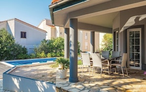 A covered outdoor seating area with a pool, stone flooring, and a view of neighboring buildings. - Charming Villa Antonija (Novalja)