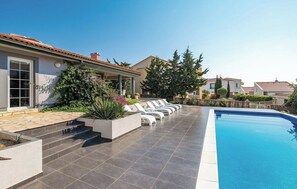 A modern outdoor pool area with a tiled deck, lounge chairs, and a clear blue pool. - Charming Villa Antonija (Novalja)