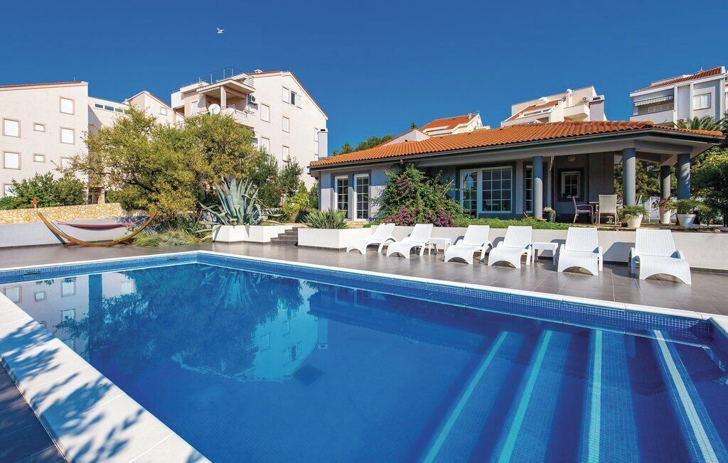 Een seizoensgebonden buitenzwembad, ligstoelen bij het zwembad