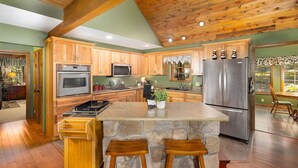 Une cuisine spacieuse avec des meubles en bois, un grand îlot central et un plan de travail en pierre.