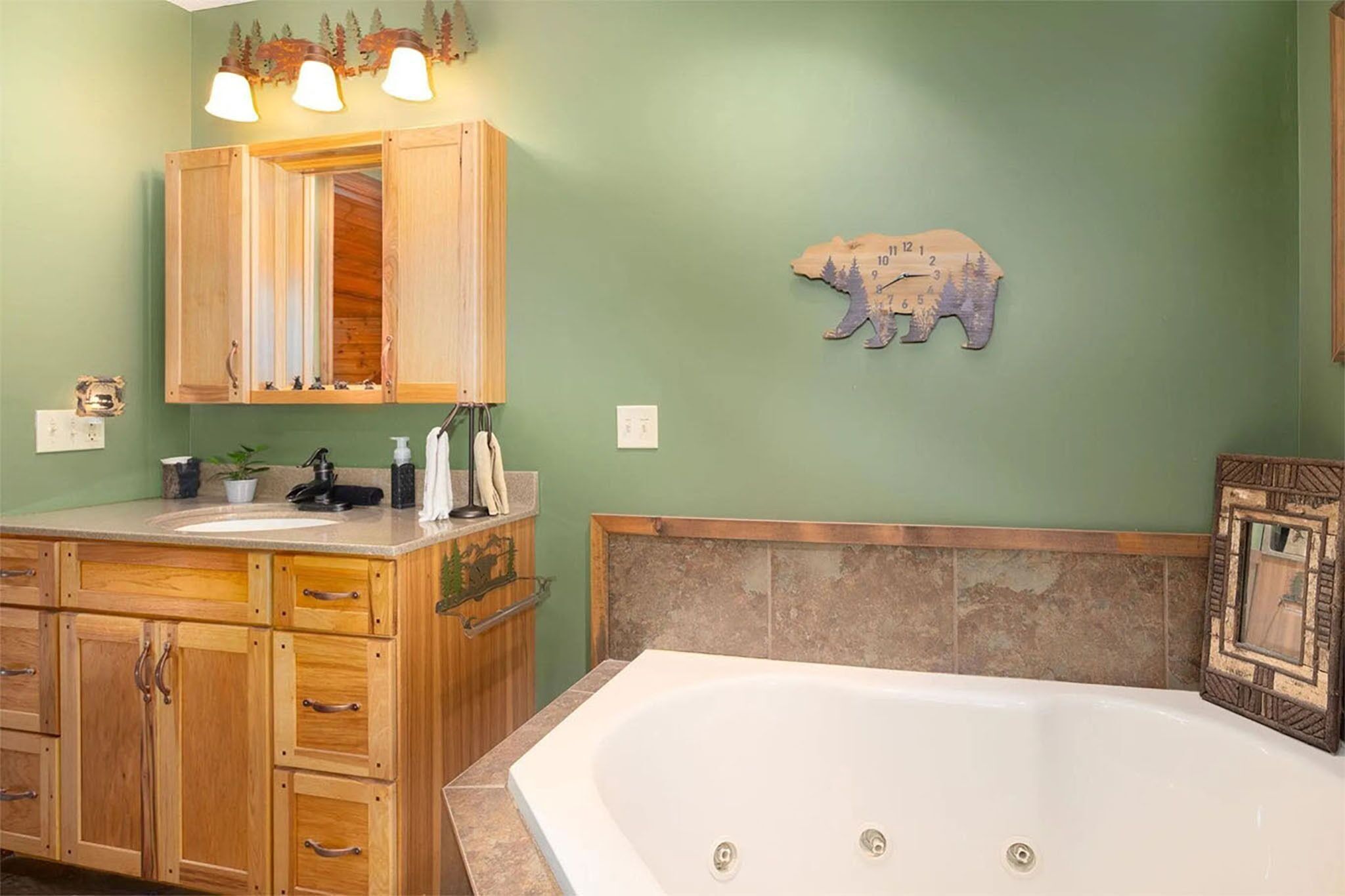 Une salle de bain avec un meuble-lavabo en bois, un grand miroir, une horloge murale et une baignoire.