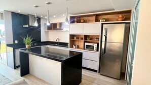 Una cocina moderna con una isla central, electrodomésticos de acero inoxidable y estantes de madera.
