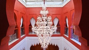 A grand chandelier in a red-walled room with arched windows and a skylight.