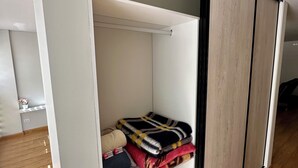 Una habitación moderna con un armario corredero, una cama con cabecera de madera y un pequeño estante con una planta en maceta.
