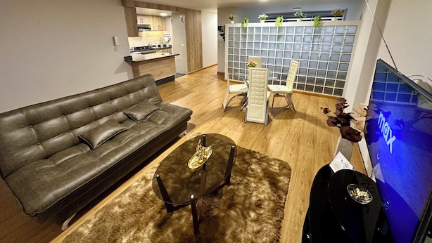 Una sala moderna con un sofá de cuero, una mesa de centro y un televisor.