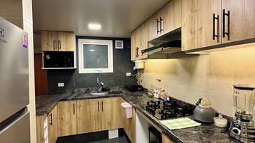 A modern kitchen with wooden cabinets, a granite countertop, and stainless steel appliances.