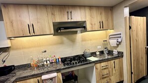 Una cocina moderna con armarios de madera, encimera de granito y estufa integrada.