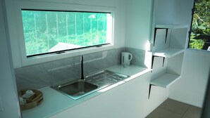 A modern kitchen with a large window, a stainless steel sink, and white cabinetry. - Hotel Laimoa (Apia)