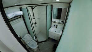 A modern bathroom with a glass-enclosed shower, a toilet, and a sink with a mirror above it. - Hotel Laimoa (Apia)