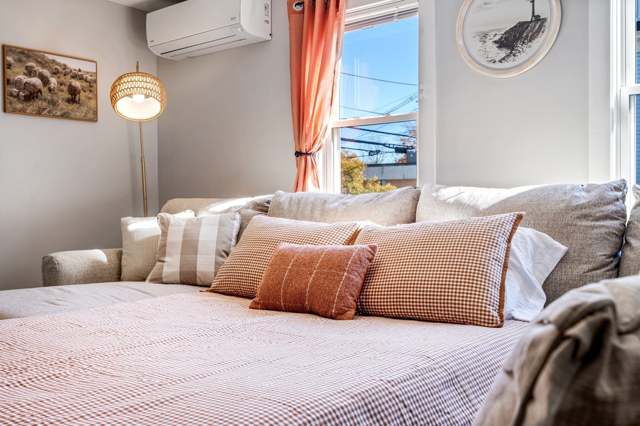 A bedroom with a bed, pillows, a floor lamp, and a window with curtains.