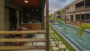 Une chambre d’hôtel moderne avec vue sur une piscine, une terrasse en bois et un balcon.