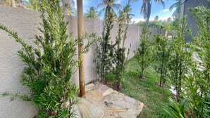 Un espace jardin aménagé avec un sentier en pierre, des palmiers et un élément décoratif aquatique.