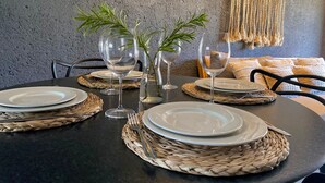 Une table à manger dressée avec des assiettes, des verres et des sets de table en fibres tressées.