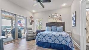 Een slaapkamer met een groot bed, een plafondventilator en uitzicht op de omgeving.