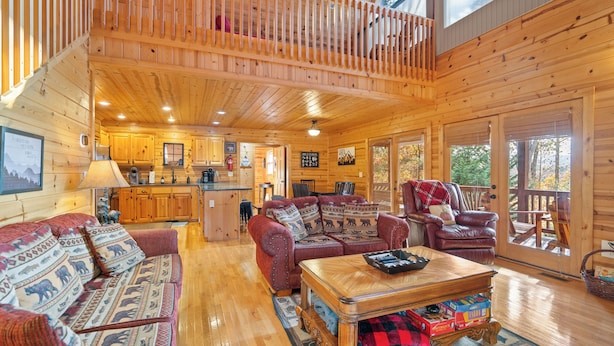 A spacious log cabin interior with a living area, a dining table, and a kitchen.