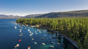A coastal area with numerous boats docked along a forested shoreline. - Super Clean - Tahoe Park Access! (Tahoe City)