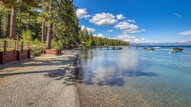 A clear lake with a wooden walkway and trees on one side, and boats on the water. - Super Clean - Tahoe Park Access! (Tahoe City)