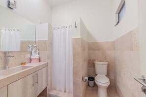 Baño con ducha, inodoro, lavabo y espejo.