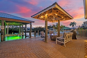 A covered outdoor area with a pool, lounge chairs, and a gazebo.