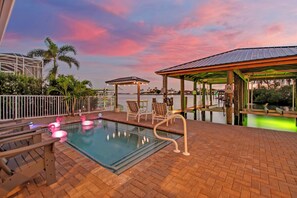 A rooftop pool area with lounge chairs, a covered seating area, and a view of the water.