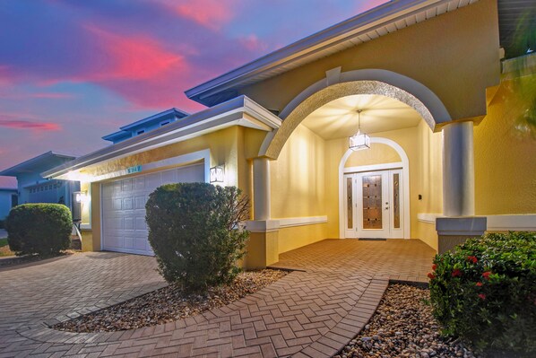 A residential house with a driveway, a garage, and a well-lit entrance.