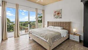 A bedroom with a large bed, a nightstand, a ceiling fan, and a balcony with a view. - Apartment #3 -1-bedroom apartment with WiFi, AC in tranquil Tarcoles (Tarcoles)