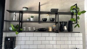 A kitchen with white subway tiles, black shelves, and various kitchen items. - Flat Itajuru (Cabo Frio)