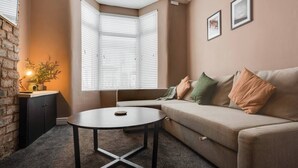 A cozy living room with a sofa, a round coffee table, and a potted plant.